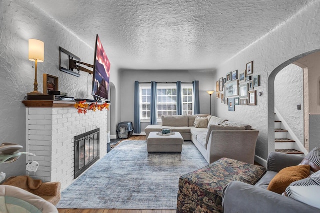 living room featuring wood-type flooring, a fireplace, and a textured ceiling