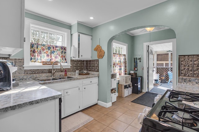 kitchen featuring sink, white cabinetry, crown molding, light tile patterned floors, and backsplash