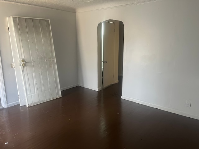 unfurnished bedroom with dark hardwood / wood-style flooring, a textured ceiling, and a closet