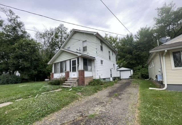 view of front of house featuring a garage, an outdoor structure, and a front lawn