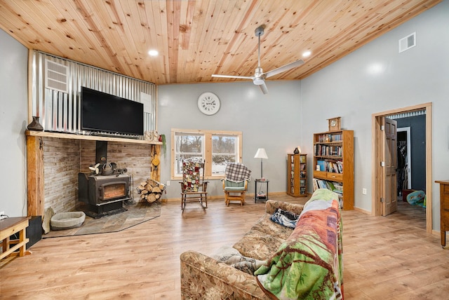 living room featuring a wood stove, ceiling fan, a high ceiling, wood ceiling, and hardwood / wood-style flooring