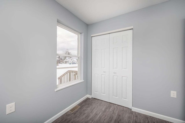 unfurnished bedroom with dark hardwood / wood-style flooring and a closet