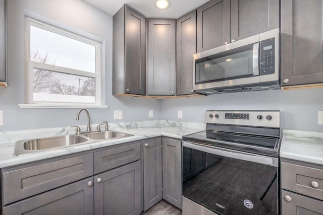 kitchen with gray cabinetry, sink, and stainless steel appliances