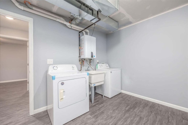 washroom with hardwood / wood-style flooring, washing machine and clothes dryer, and water heater