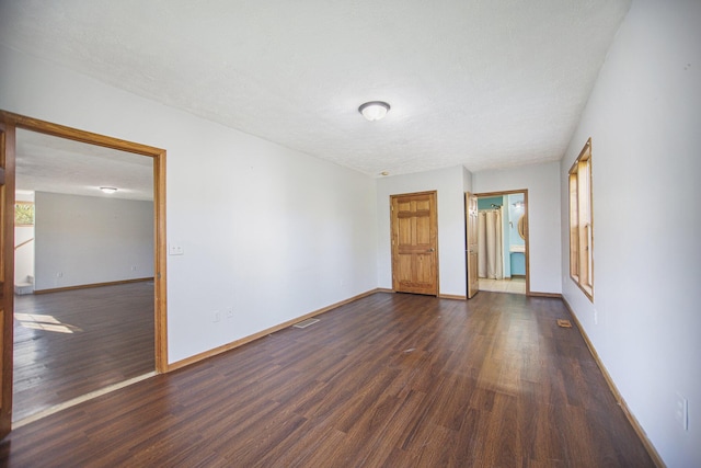 spare room featuring a textured ceiling and dark wood-type flooring