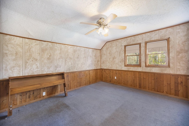 carpeted spare room featuring ceiling fan, a textured ceiling, and vaulted ceiling