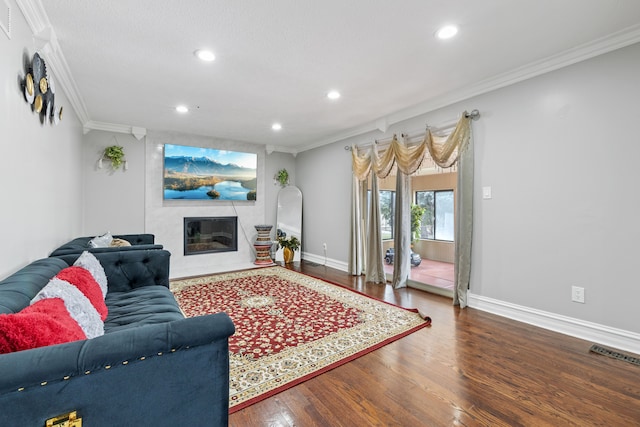 living room featuring hardwood / wood-style floors, crown molding, and a fireplace