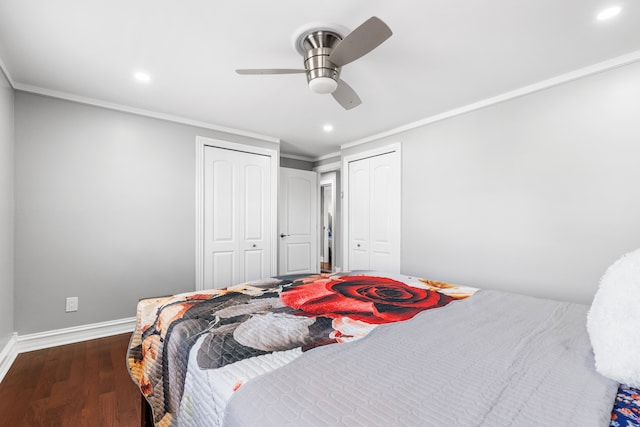 bedroom with ornamental molding, dark hardwood / wood-style floors, ceiling fan, and multiple closets