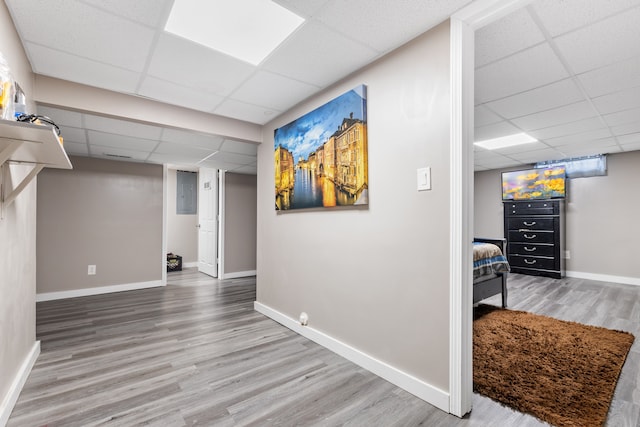 basement featuring a paneled ceiling and hardwood / wood-style flooring