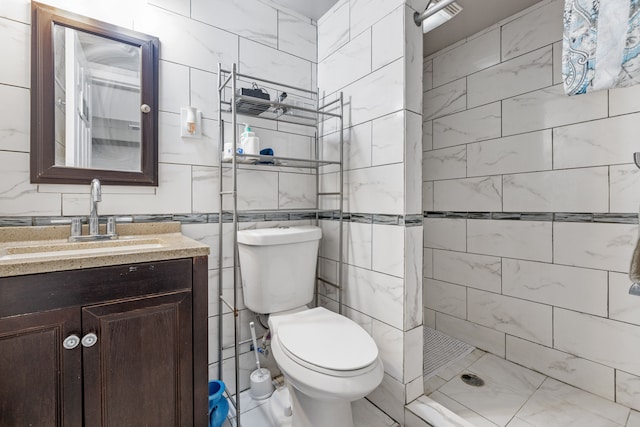 bathroom with tiled shower, vanity, toilet, and tile walls