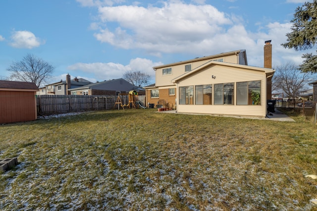 rear view of house featuring a yard, a playground, and a sunroom