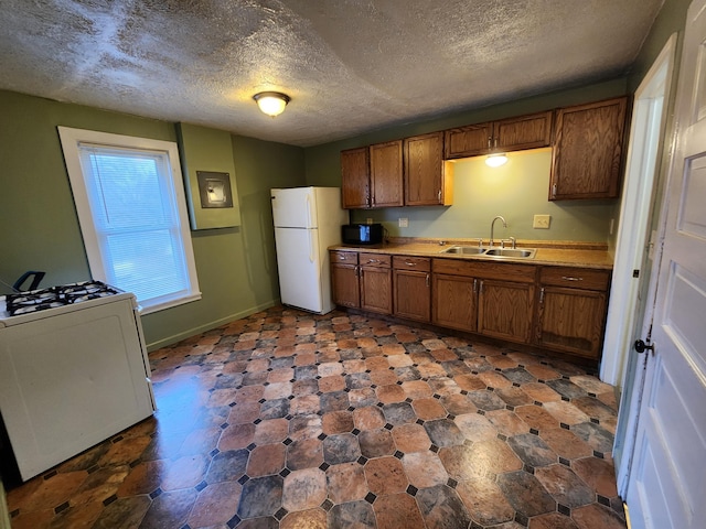 kitchen featuring a textured ceiling, white appliances, and sink
