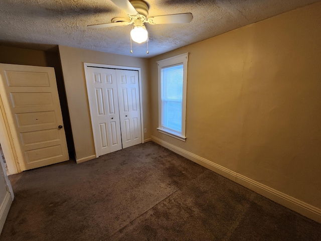 unfurnished bedroom featuring dark colored carpet, ceiling fan, a textured ceiling, and a closet