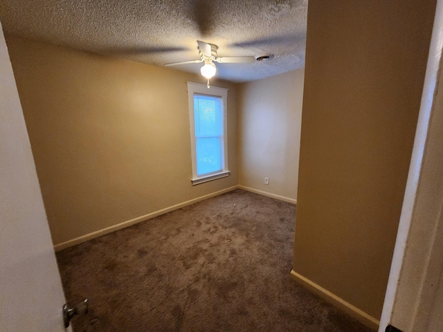 empty room featuring ceiling fan, a textured ceiling, and dark colored carpet