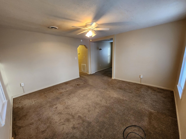 spare room featuring ceiling fan, a textured ceiling, and dark colored carpet