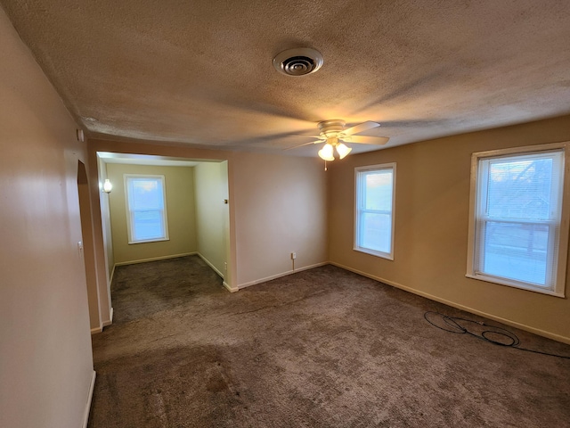 carpeted empty room featuring ceiling fan, a healthy amount of sunlight, and a textured ceiling