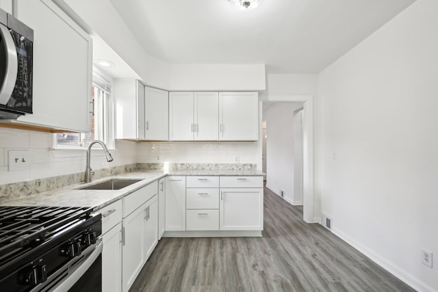 kitchen featuring light stone countertops, light hardwood / wood-style flooring, white cabinetry, and sink