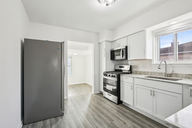 kitchen featuring white cabinets, sink, light hardwood / wood-style flooring, appliances with stainless steel finishes, and tasteful backsplash