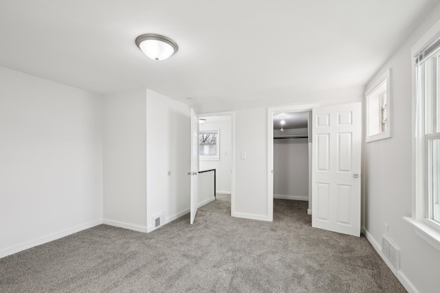 unfurnished bedroom with light colored carpet, a walk in closet, and a closet