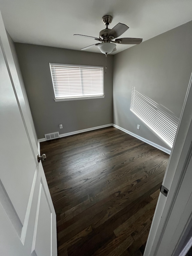 unfurnished room with visible vents, baseboards, dark wood-type flooring, and ceiling fan