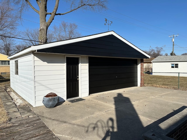 detached garage with concrete driveway and fence