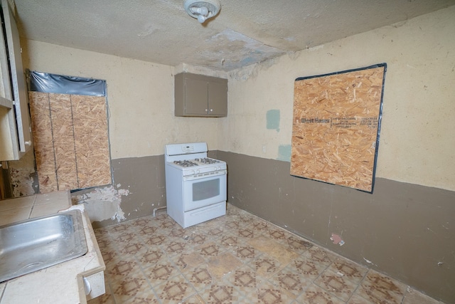 kitchen featuring gray cabinets, white gas range, and sink