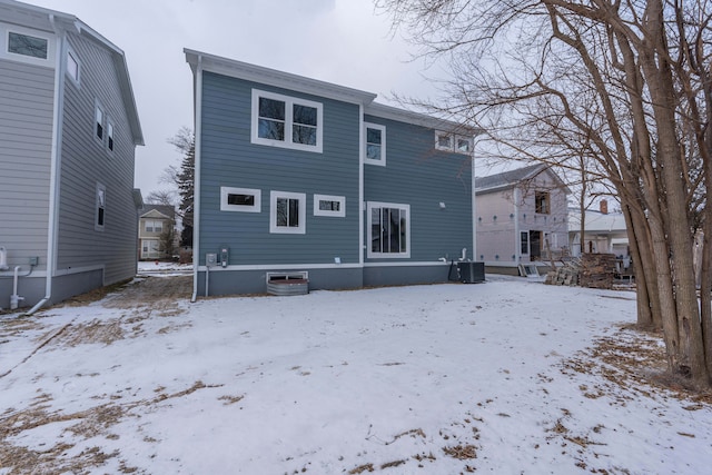 snow covered rear of property featuring central AC