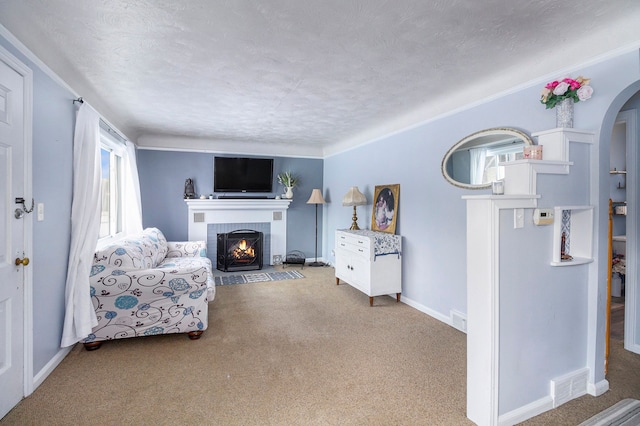 living room featuring a brick fireplace, a textured ceiling, and light colored carpet