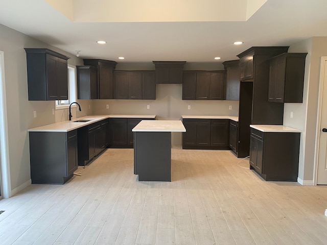 kitchen with sink, a kitchen island, black refrigerator, and light hardwood / wood-style floors