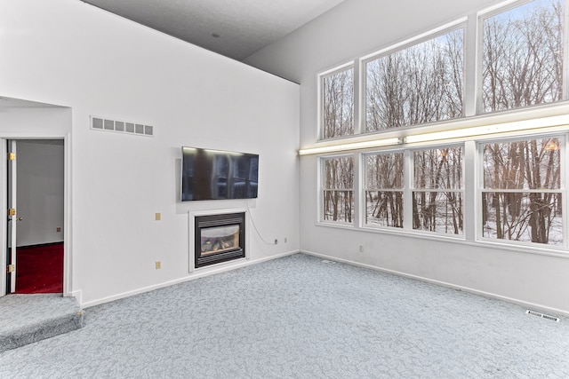 unfurnished living room with carpet flooring and high vaulted ceiling