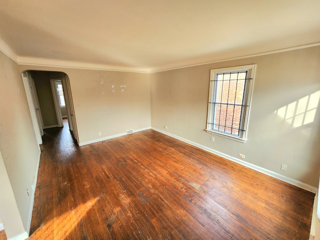 empty room with dark hardwood / wood-style flooring and crown molding