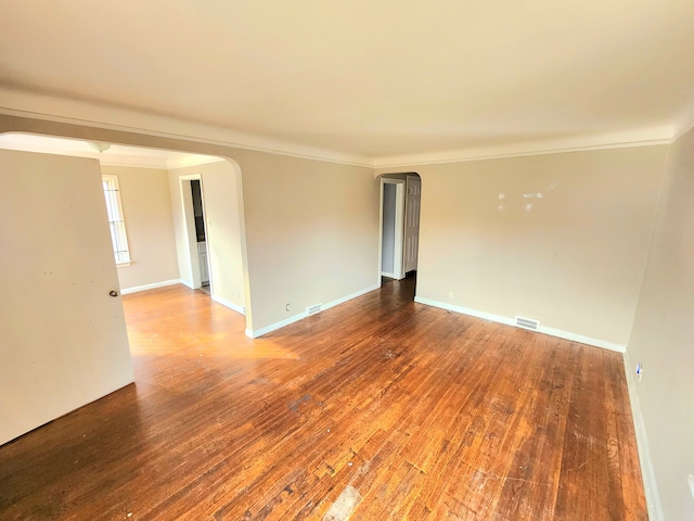 empty room with ornamental molding and hardwood / wood-style flooring