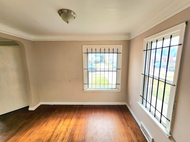 unfurnished room featuring dark wood-type flooring and ornamental molding