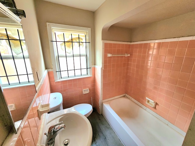 full bathroom featuring a healthy amount of sunlight, tile walls, sink, and hardwood / wood-style flooring