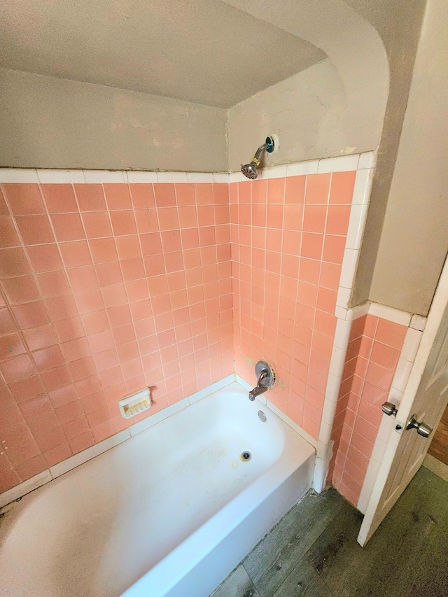 bathroom with hardwood / wood-style flooring, tile walls, and tiled shower / bath