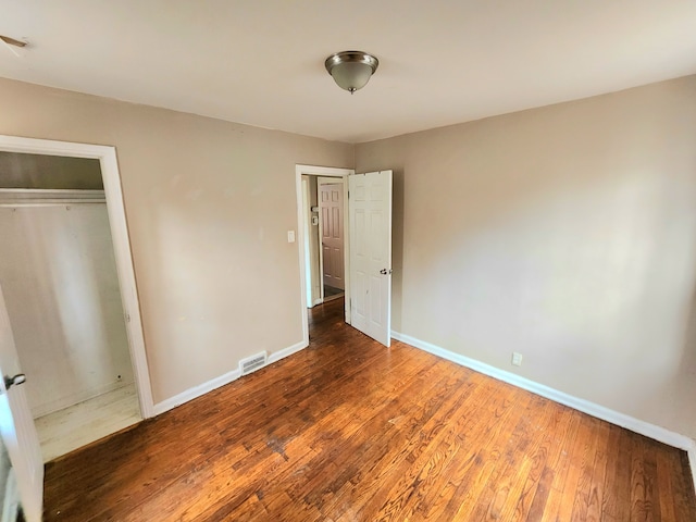 unfurnished bedroom with dark hardwood / wood-style floors and a closet