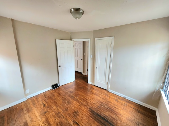 unfurnished bedroom featuring dark wood-type flooring and a closet