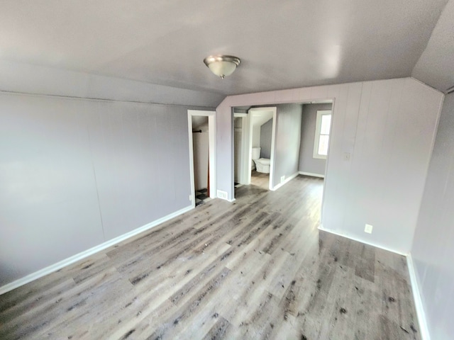 spare room featuring light wood-type flooring and vaulted ceiling