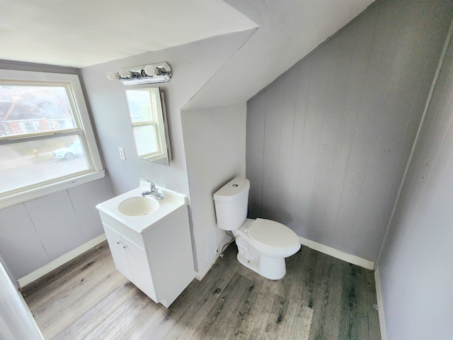 bathroom featuring toilet, vanity, wooden walls, and hardwood / wood-style floors