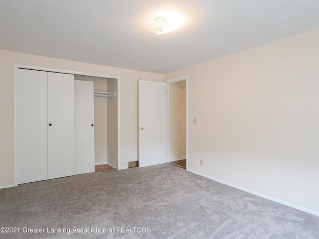 unfurnished bedroom featuring a closet and light colored carpet