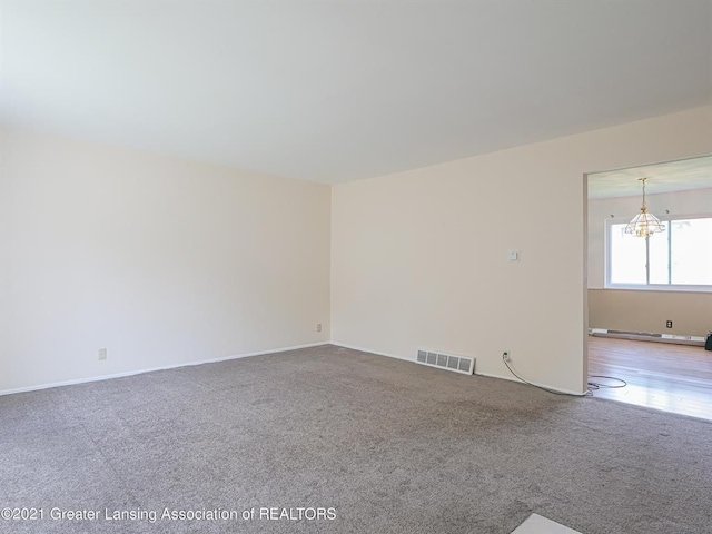 empty room featuring a chandelier and carpet floors