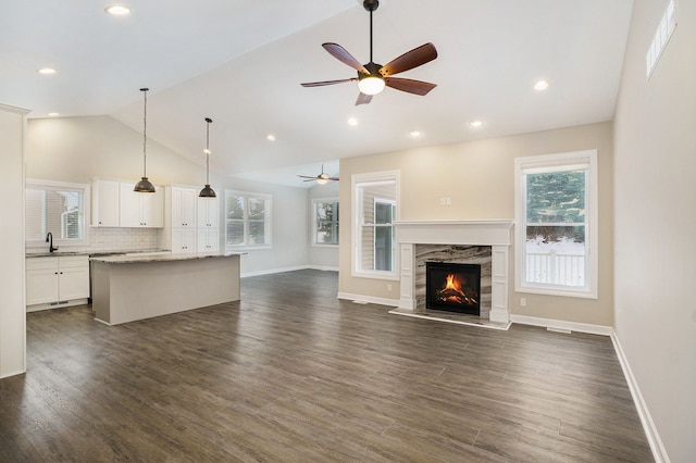 unfurnished living room featuring a fireplace, dark hardwood / wood-style floors, vaulted ceiling, and ceiling fan