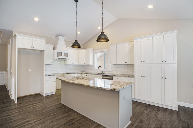 kitchen with white cabinets, a kitchen island, and light stone countertops