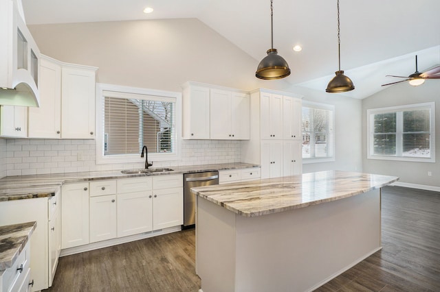 kitchen with decorative backsplash, stainless steel dishwasher, a kitchen island, sink, and white cabinetry