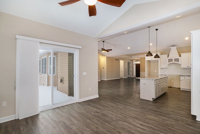 kitchen featuring white cabinetry, a center island, premium range hood, backsplash, and lofted ceiling