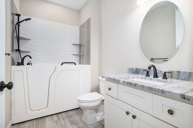 bathroom featuring a bathtub, vanity, wood-type flooring, and toilet