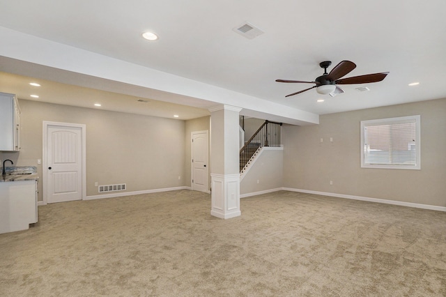 basement featuring ceiling fan, light colored carpet, and sink