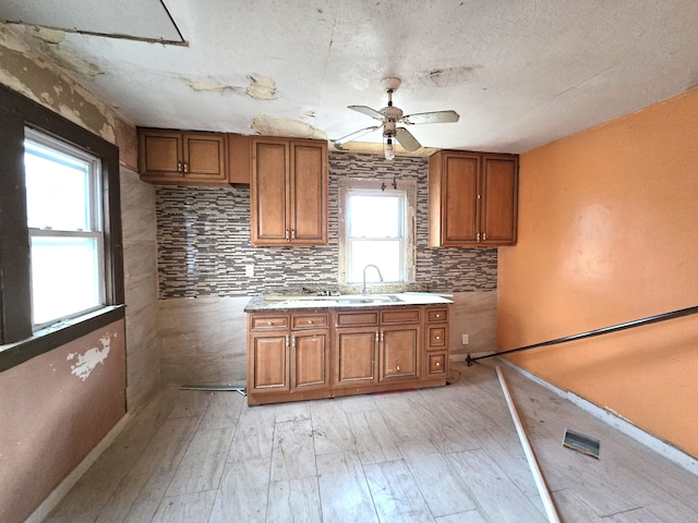 kitchen with ceiling fan, tasteful backsplash, a wealth of natural light, and light hardwood / wood-style flooring