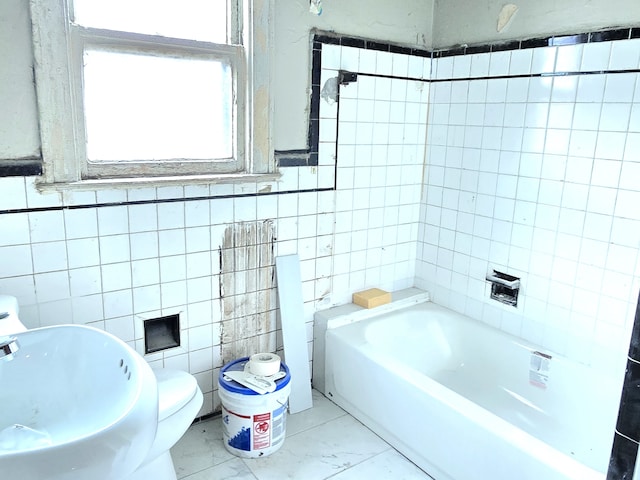 bathroom featuring sink, a bathtub, tile walls, and toilet