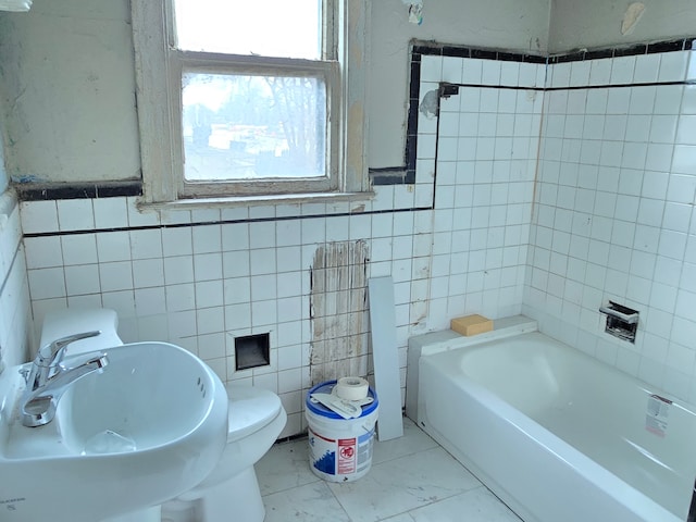 bathroom featuring toilet, sink, tile walls, and a tub